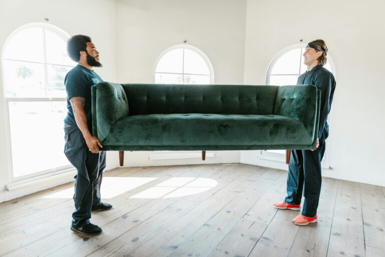 Two movers carrying a green velvet sofa in the concept of man and van in Surbiton.